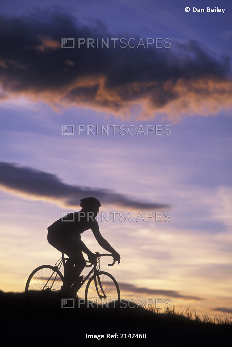 Silhouette Of A Road Biker Riding Against A Colorful Sunset Sky
