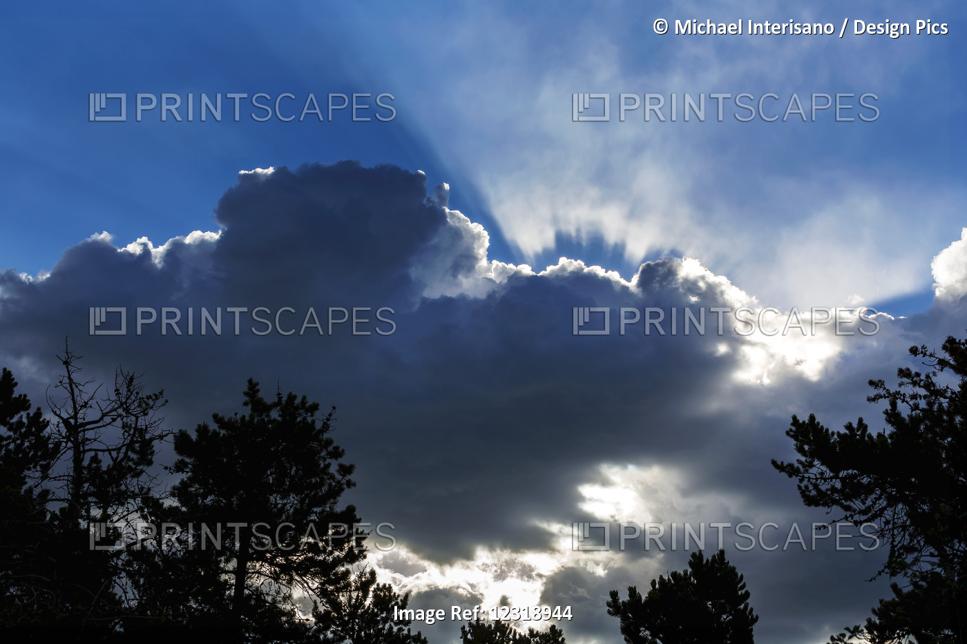 Dramatic Backlit Cloud Covered Sky With Sun Rays Beaming Through The Opening; ...