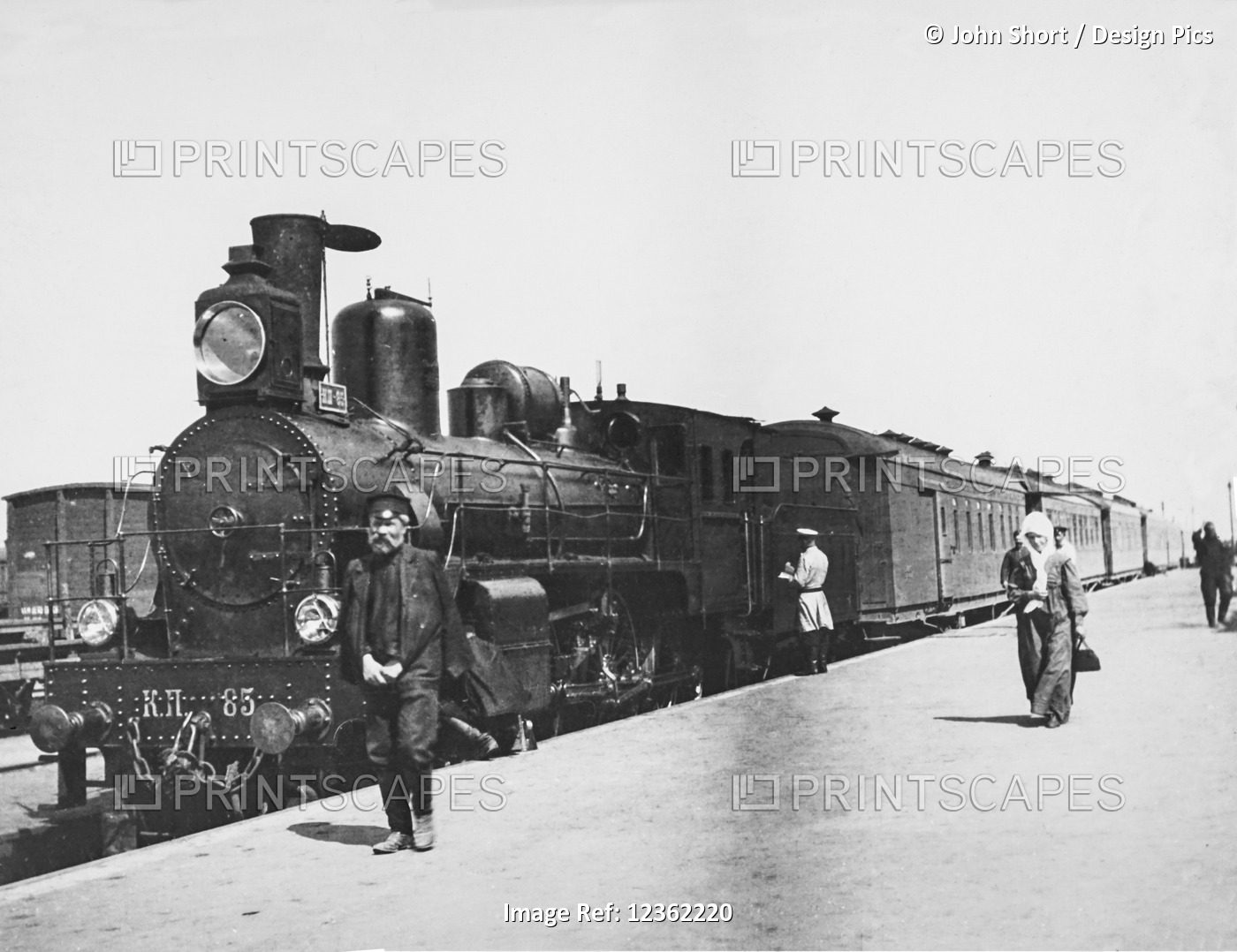 Vintage black and white image of passengers and a worker on the platform of a ...