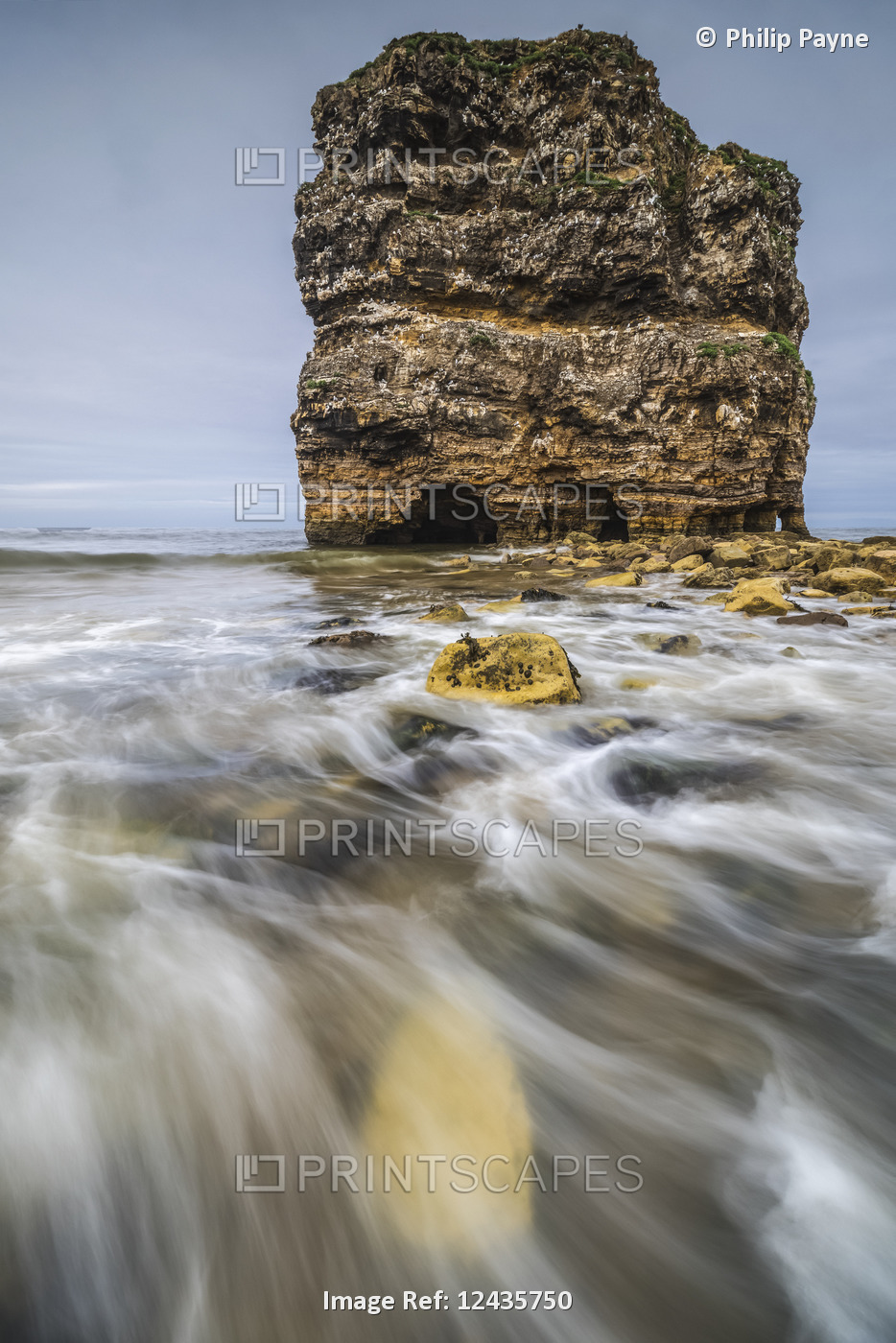 Water washing over the rocks on the shore by a large sea stack; South Shields, ...