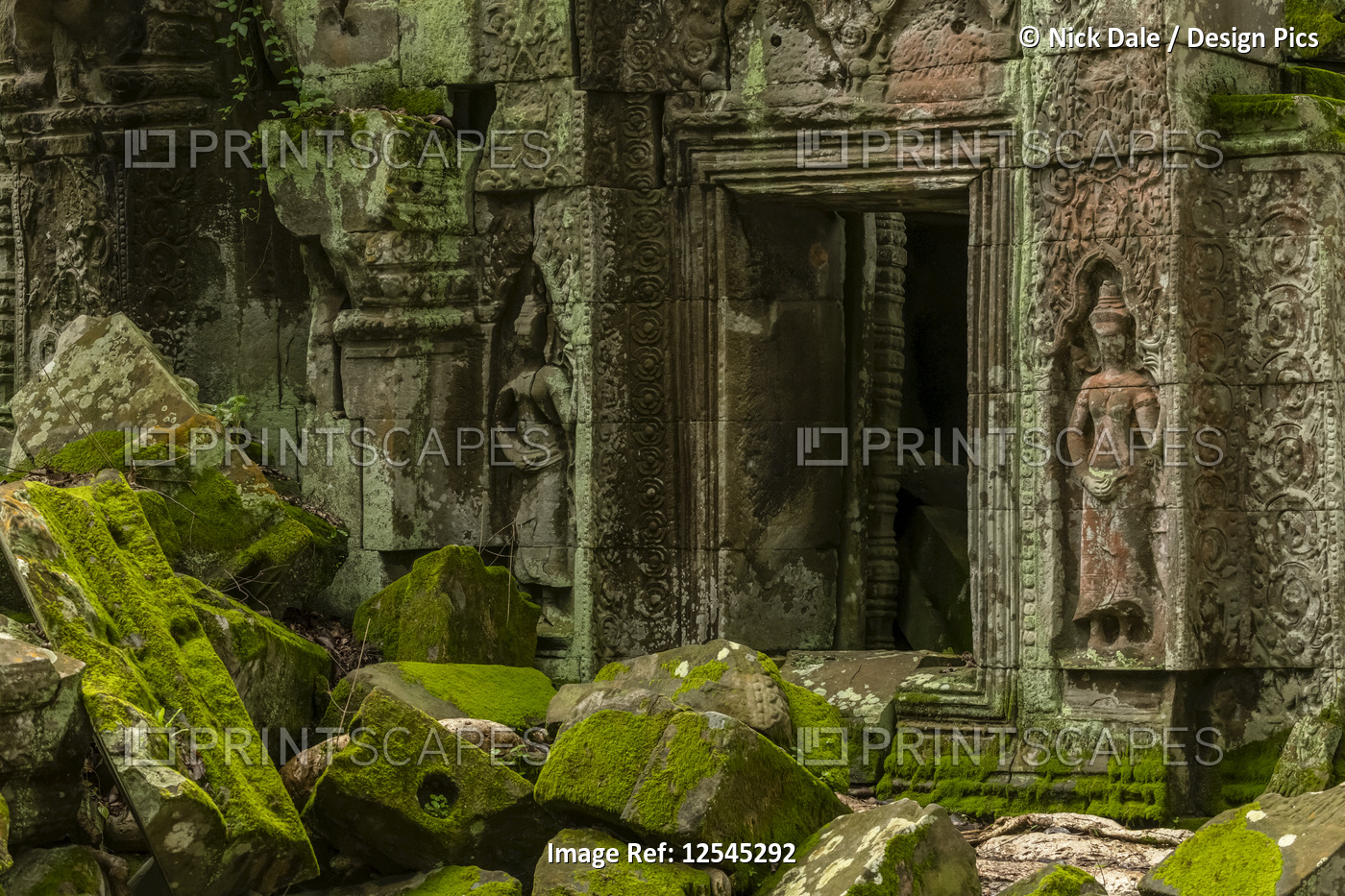 Statues and fallen rocks by temple doorway, Ta Prohm, Angkor Wat; Siem Reap, ...