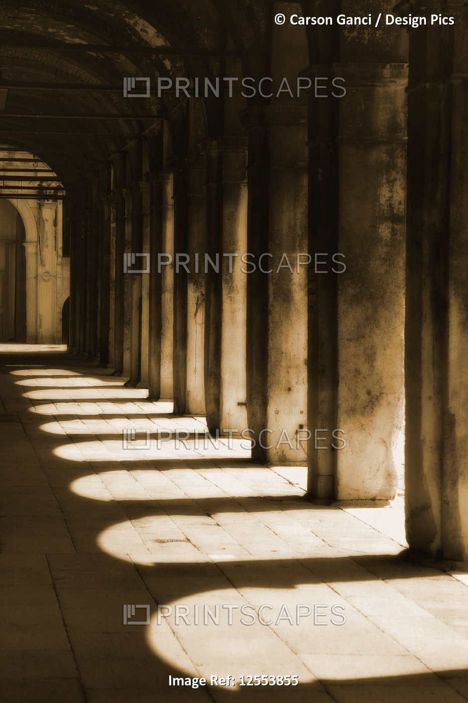 Walkway with shadows of arches and columns on the ground cast by bright ...