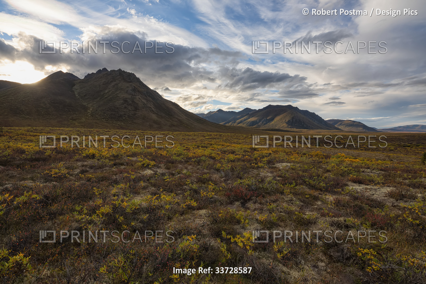 Sunset light illuminates the mountains and landscape of the Dempster Highway in ...