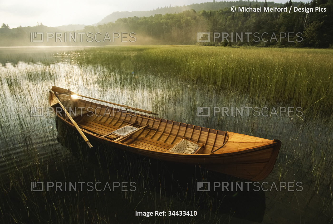 Adirondack guide canoe floats on Connery Pond at sunrise in Adirondack Park; ...