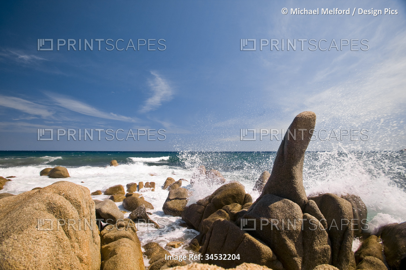 Blue water splashing against rocks on the beach on the Cote d'Azure; French ...