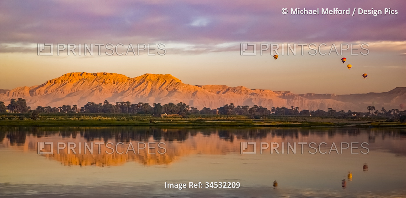 At sunrise, hot air balloons hover above the Nile; Luxor, Egypt