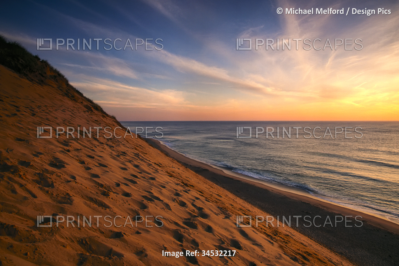 Sunrise paints the sky orange over the shoreline of Coastguard Beach; Cape Cod, ...