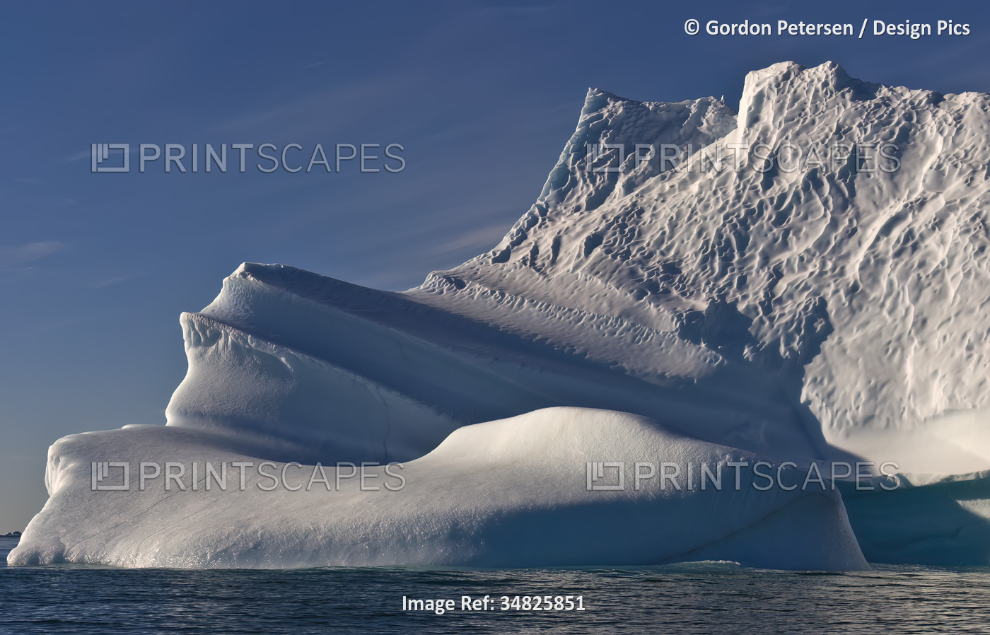 Iceberg with rugged formation in tranquil water with blue sky, near Qaanaaq ...